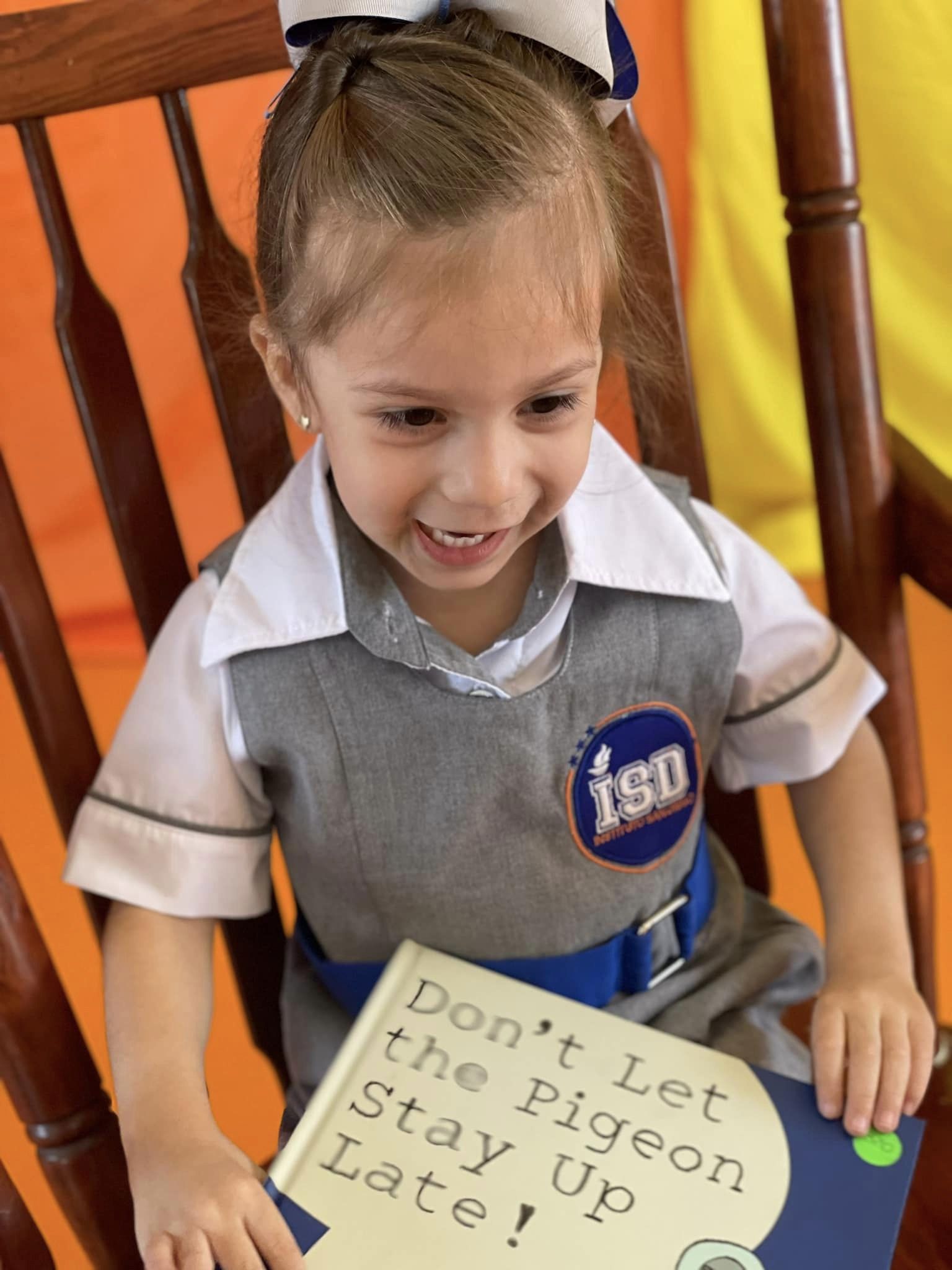 Alumna con el uniforme del Instituto San Diego sonríe con un libro de cuentos en las manos